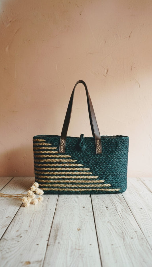 Woven handbag with black handle on a wooden surface against a beige wall, This is a sabai grass tote