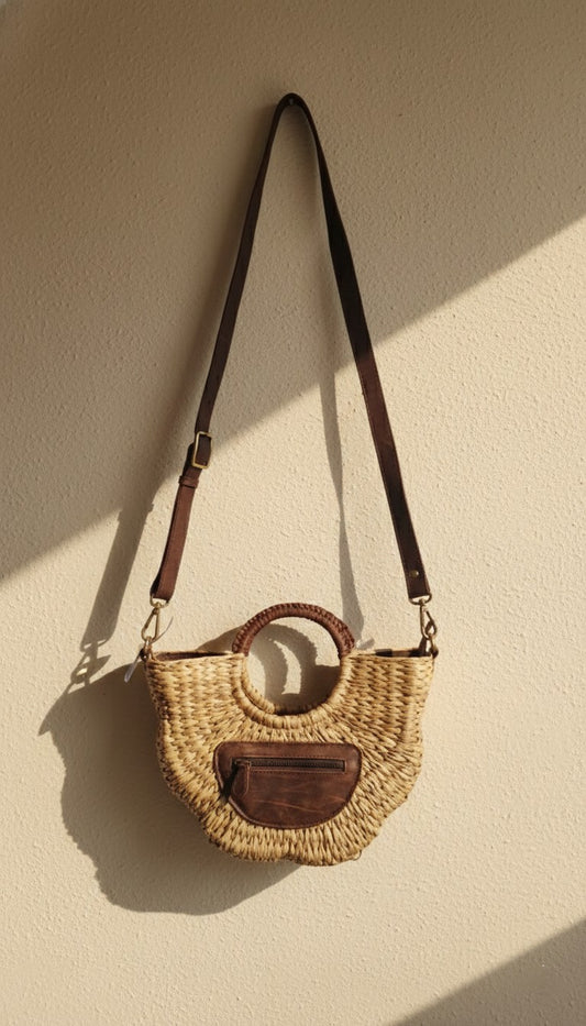Woven handbag with leather accents on a beige background. Sustainable fashion accessories. A crossbody bag, 