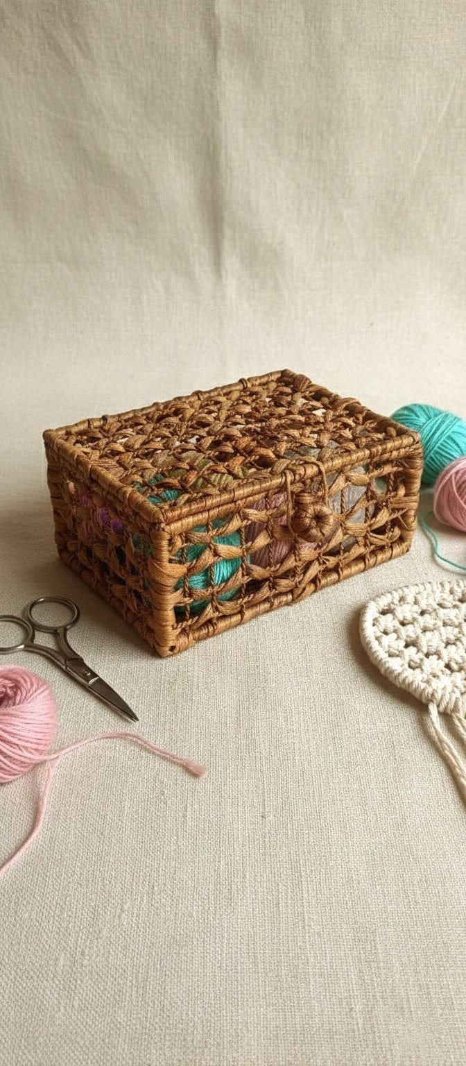 Woven water hyacinth basket with yarn and crochet hook on a beige surface