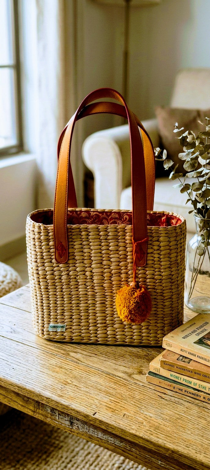 Hand Woven kauna grass bag with leather handles on a wooden surface in a home setting